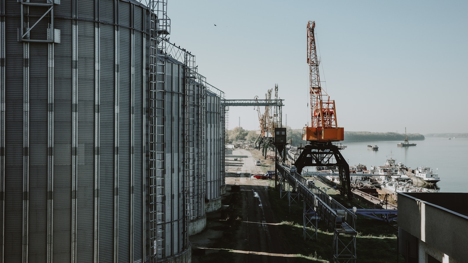 Illustrative view of waterfront silos, cranes and port logistics infrastructure.