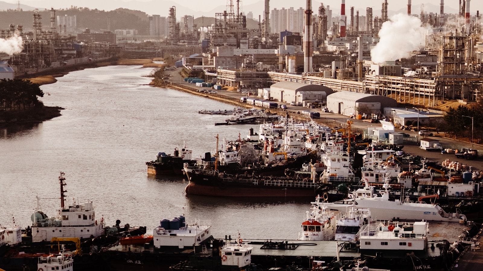 Illustrative view of ships alongside an industrial waterfront with refinery structures.