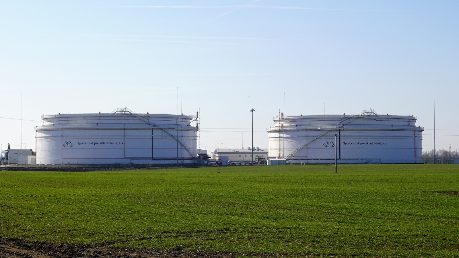 Illustrative aerial view of white petroleum storage tanks and connecting pipework.