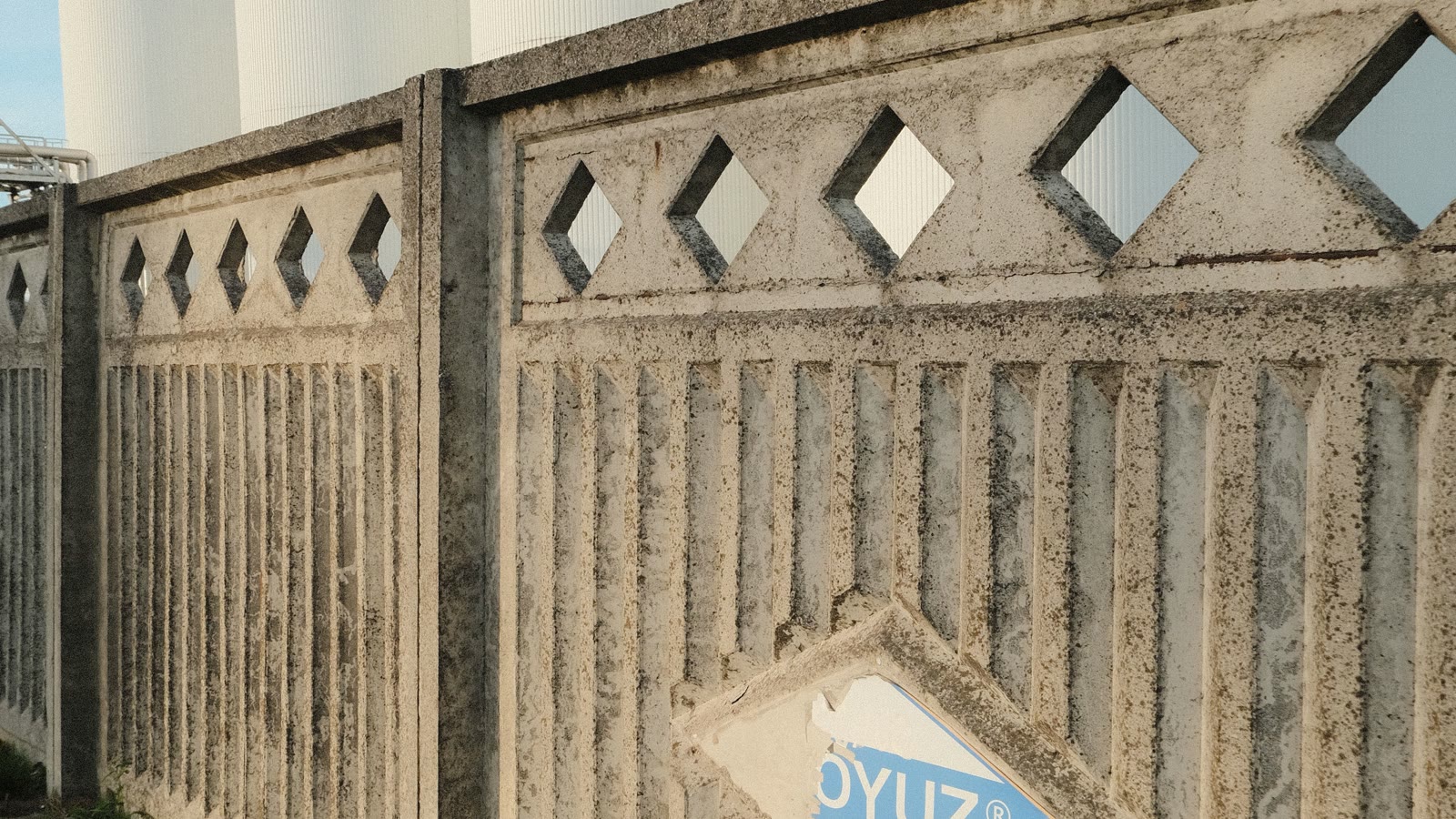Illustrative view of cylindrical petroleum storage tanks behind a perimeter wall.