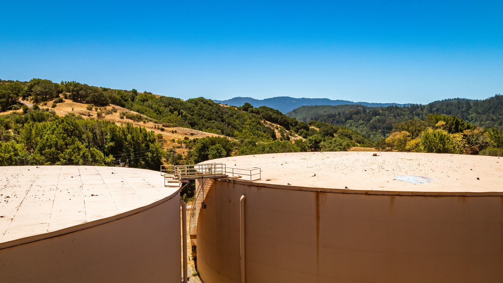Illustrative wide view of large industrial storage tanks under a clear sky.