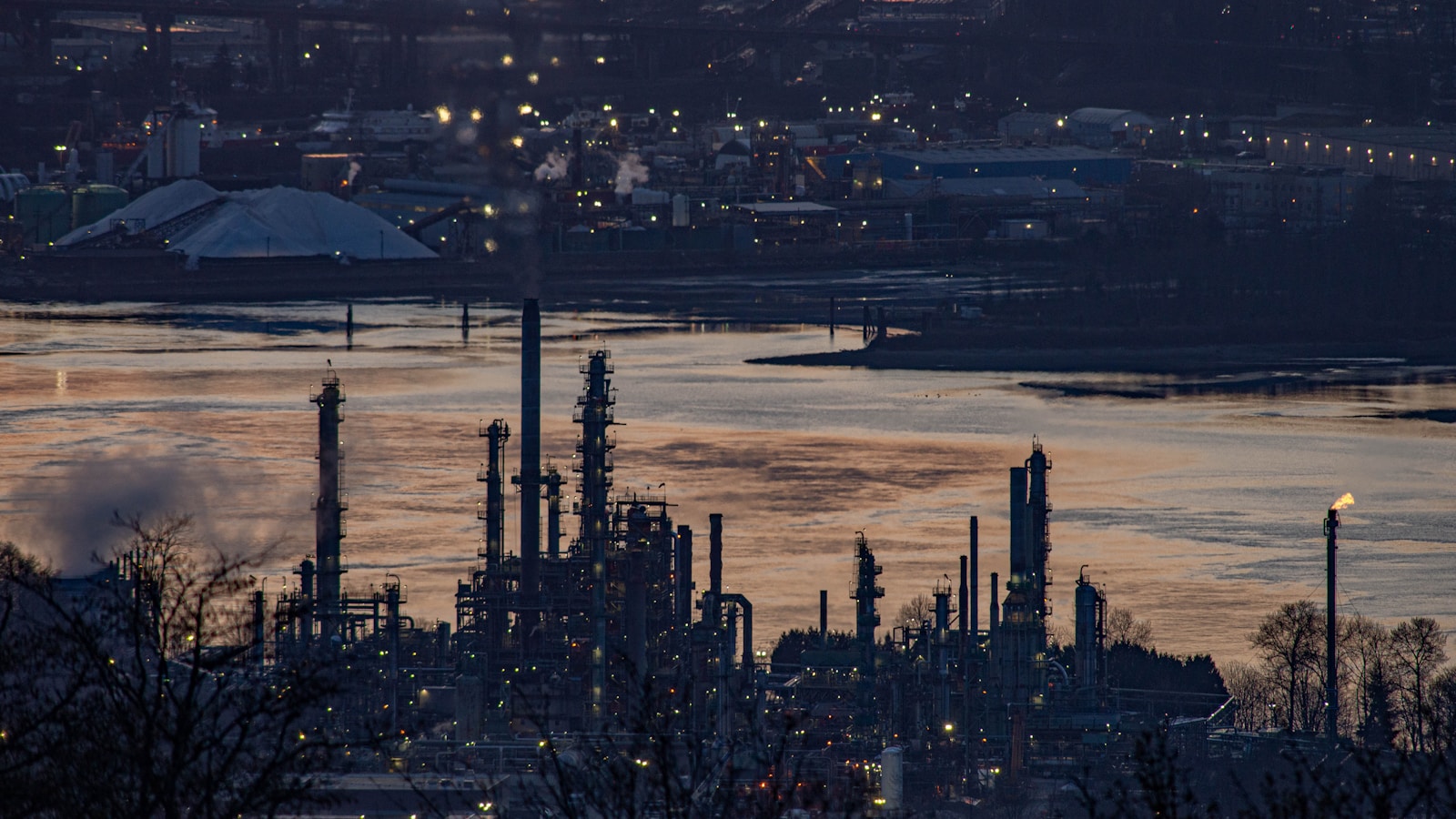 Illustrative dusk view of a refinery and waterfront industrial infrastructure.