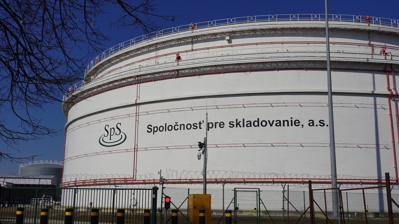 Illustrative wide view of petroleum storage tanks under a clear sky.